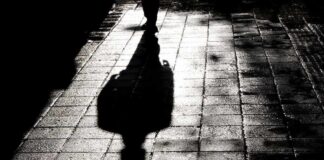 Silhouette shadow of a person walking on a wet pavement