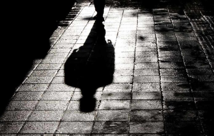 Silhouette shadow of a person walking on a wet pavement