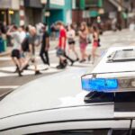 Rugby Send-Off Turns Horror police car roof light bar with blue lights near a busy crosswalk