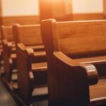 Report Details Abuse Across Three Dioceses Wooden church pews in warm sunlight