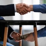 Food Aid Turned Cocaine Currency Two people shake hands while exchanging cash under a table