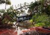 Midnight Roar Triggers Mass Evacuation house by flooded canal with fallen palm trees