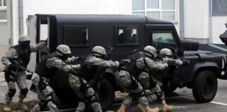 Tactical team advances beside an armored vehicle