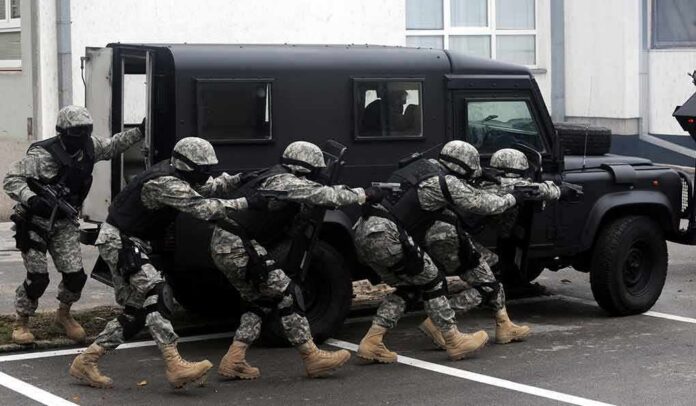 shutterstock_135978617 Tactical team advances beside an armored vehicle