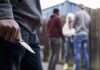 Person holding a folding knife near a group of people in an alley