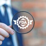 Magnifying glass held by person in suit showing FDA badge icon