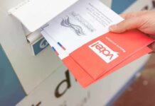 Election Safeguards Put To The Test Hand dropping mail-in ballots into a drop box