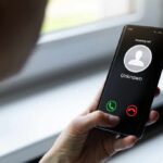 Person holding smartphone with unknown caller screen