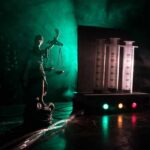 Two Lethal Doses Fail To Kill Death Row Inmate Lady Justice statue beside medical syringes with moody green light
