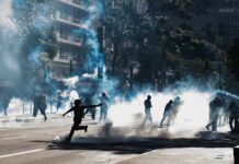 Tear Gas Chaos Grips Paris Protesters running through tear gas on a city street