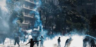 Protesters running through tear gas on a city street