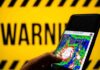 Hand holds smartphone showing cyclone radar map against warning sign