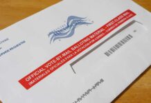 Postal Dump Exposes Voting Weak Spot Mail-in ballot envelope with red label on wooden table