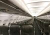 Airplane cabin with empty rows of economy seats and overhead bins