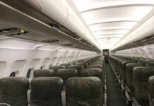 Airplane cabin with empty rows of economy seats and overhead bins