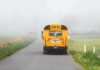 Yellow school bus on a foggy rural road
