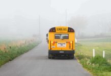 Yellow school bus on a foggy rural road