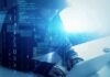 School Data RAIDED – Millions At Risk Hooded figure using a laptop with digital code overlay
