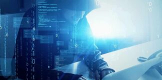Hooded figure using a laptop with digital code overlay
