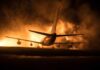 Airplane on runway with large fire and smoke at night