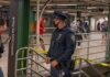 Noon Gunshot Shocks Times Square Corridor Police officer stands in a subway station near caution tape