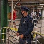 Noon Gunshot Shocks Times Square Corridor Police officer stands in a subway station near caution tape