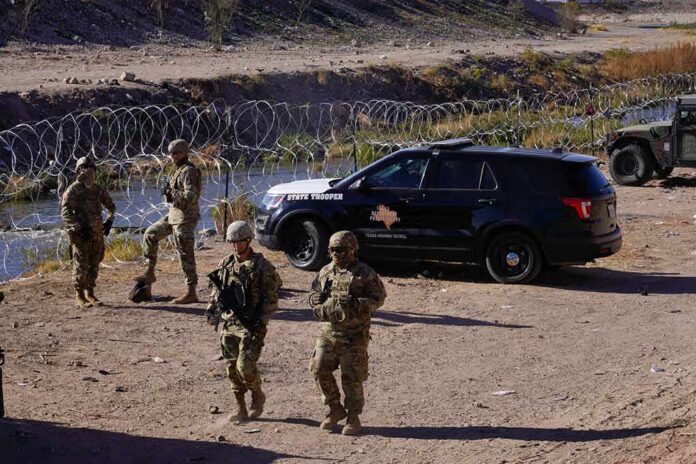 shutterstock_2241074351 Soldiers stand near barbed wire beside a police SUV