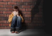 Parents Rush As Gunfire Hits Oregon School boy sitting against brick wall covering his face