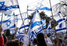 Netanyahu Reckoning Starts Now Crowd waving Israeli flags outdoors