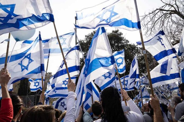 shutterstock_2264581927-1 Crowd waving Israeli flags outdoors
