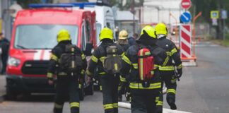 Deadly Blaze, Gunman Triggers Citywide Shock Firefighters walking toward a scene with hoses and a red emergency van