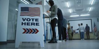 Senator Seeks Answers On Military Election Role Vote here sign at a polling station with people in line
