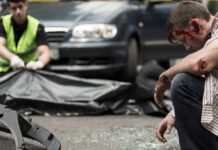 Injured man sitting at a car crash scene