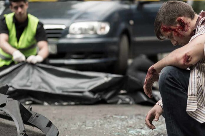 shutterstock_384619159 Injured man sitting at a car crash scene